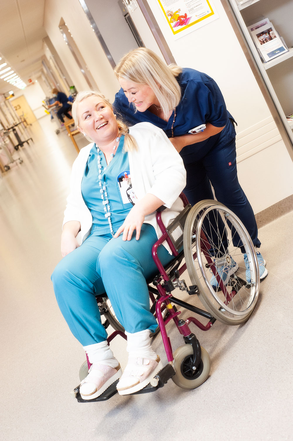 Sillaisen akuuttikuntoutusosastolla on töissä hauskaa muulloinkin kuin kuvaustilanteessa, toteavat Jenni Hirvonen ja Mari Matikainen hassutellessaan pyörätuolilla.