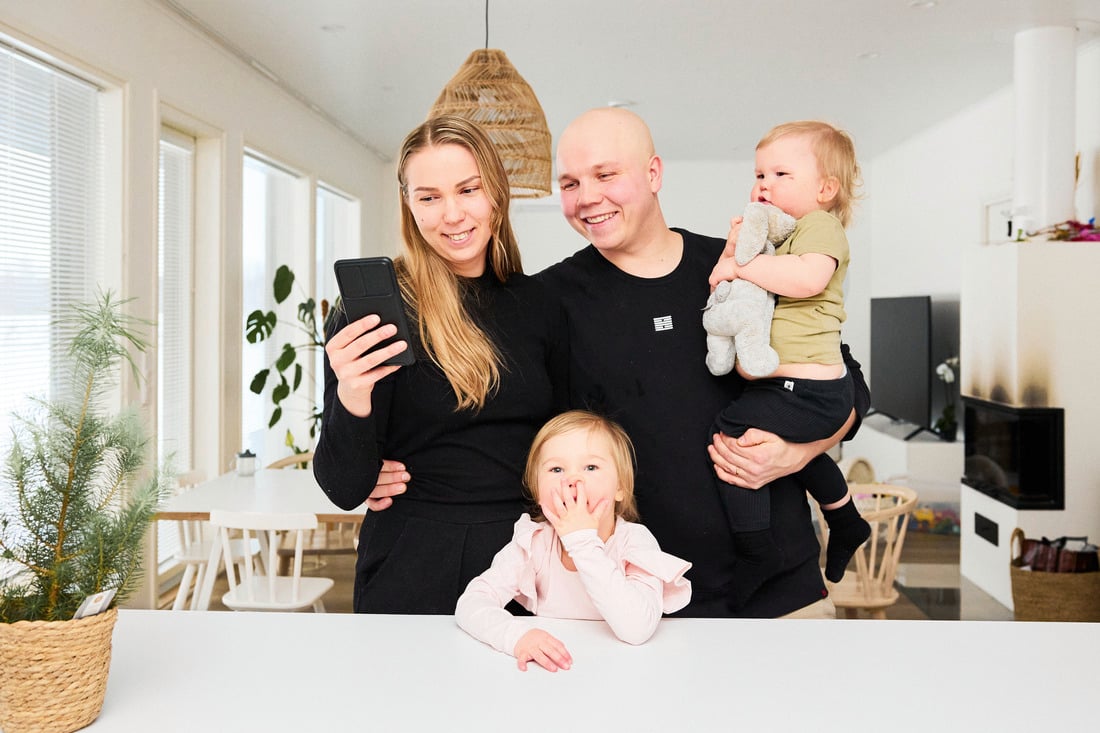Perhe kännykän kanssa keittiössä