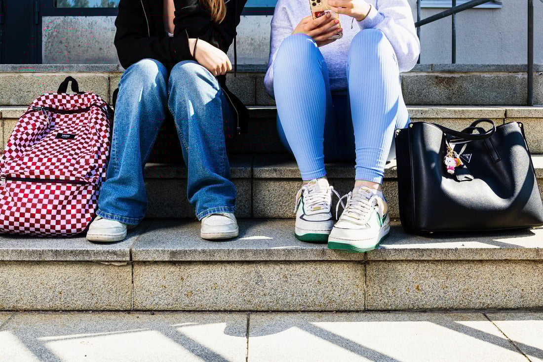 Kaksi nuorta istumassa reppujen kanssa kiviportailla