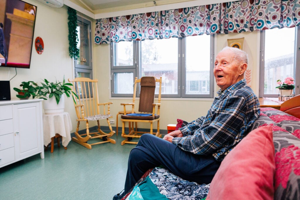 Asukas istuu oleskeluhuoneen sohvalla.