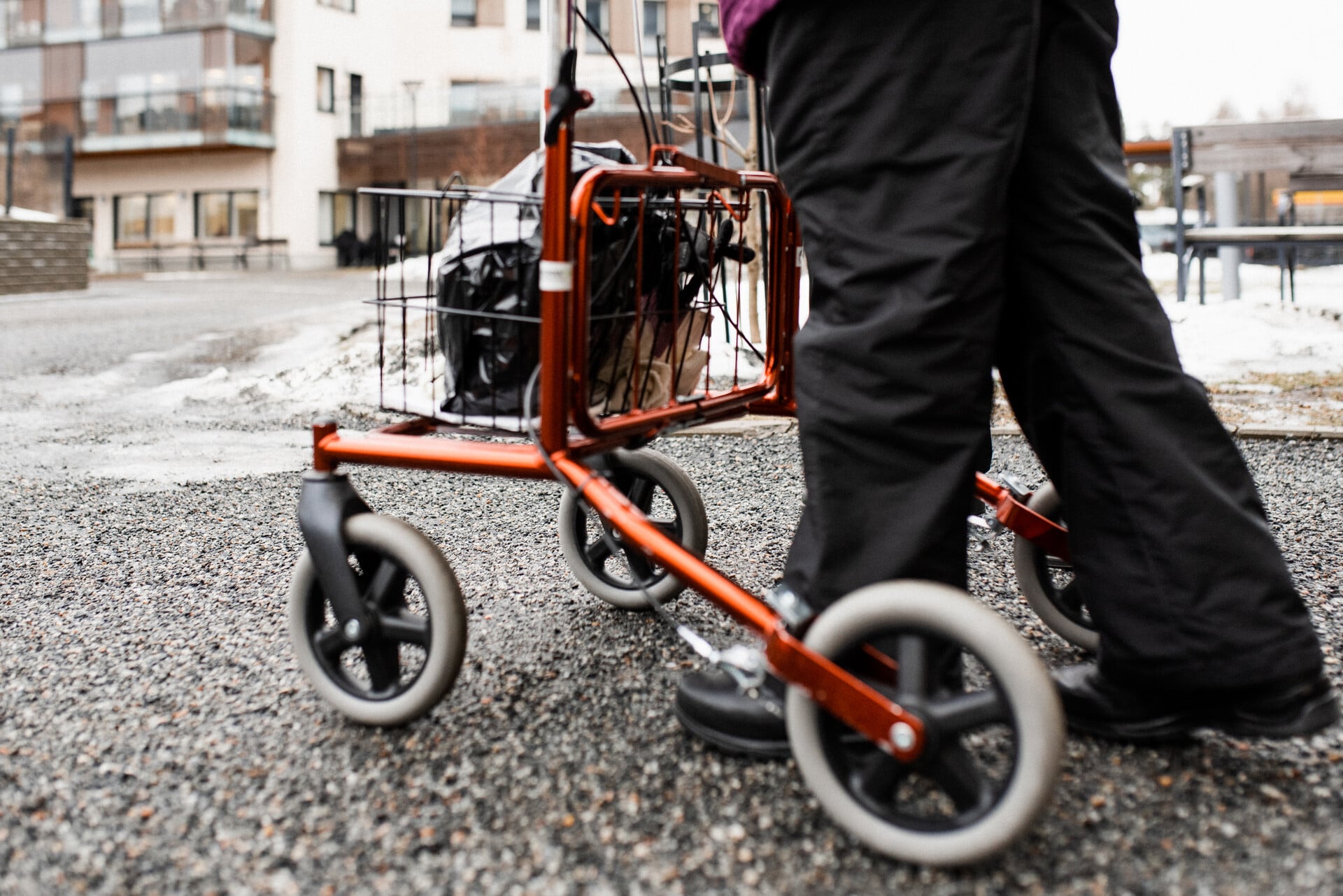 Ikääntynytkävelee rollaattorin kanssa ulkona.