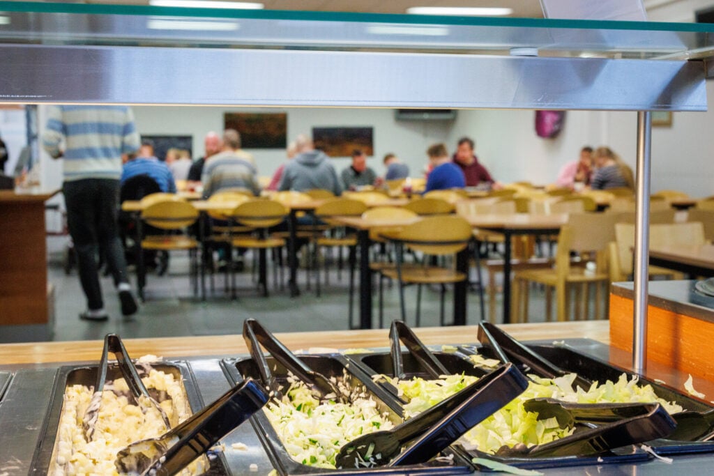 Ruokala. Kuvan etualalla salaatit ja taustalla ihmiset istumassa pöydissä.