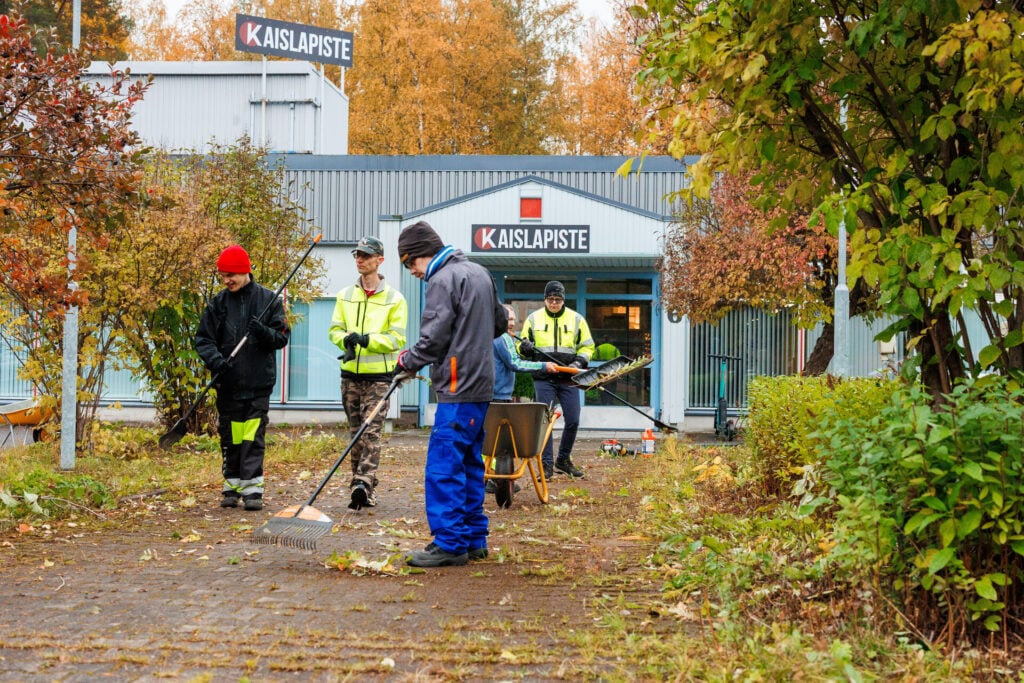 Viisi henkilöä tekemässä pihatöitä.